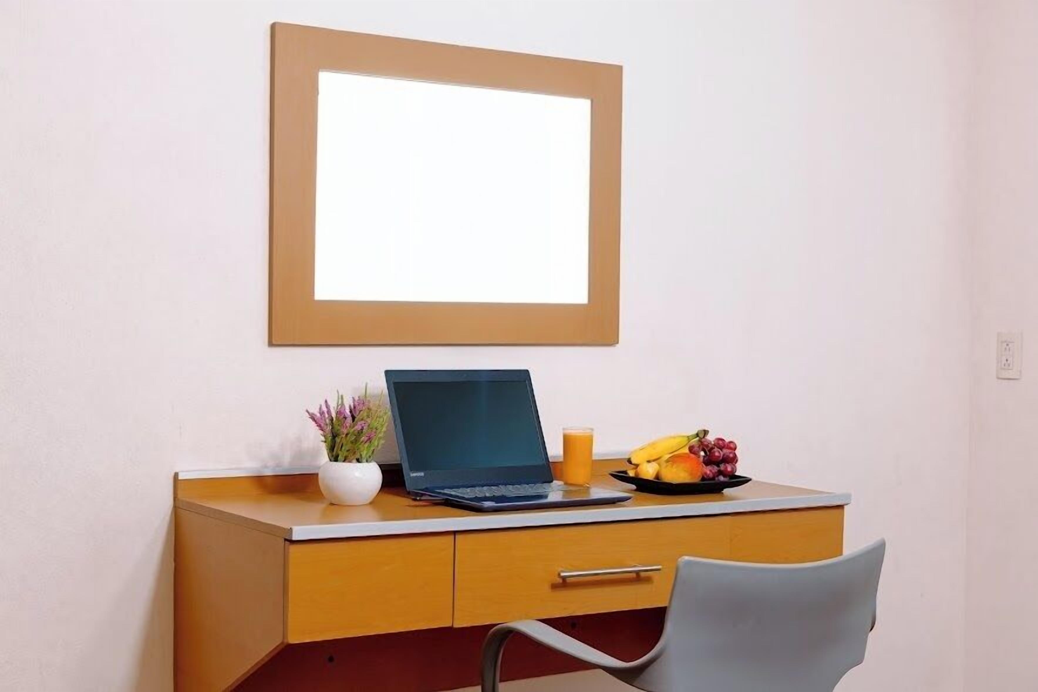 A modern office space with a desk, laptop, and a fruit plate.