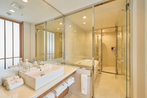 A modern bathroom with a large mirror, two sinks, and a glass-enclosed shower.