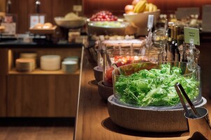 A buffet with various food items including a glass bowl of salad, bowls of fruit, and other dishes.