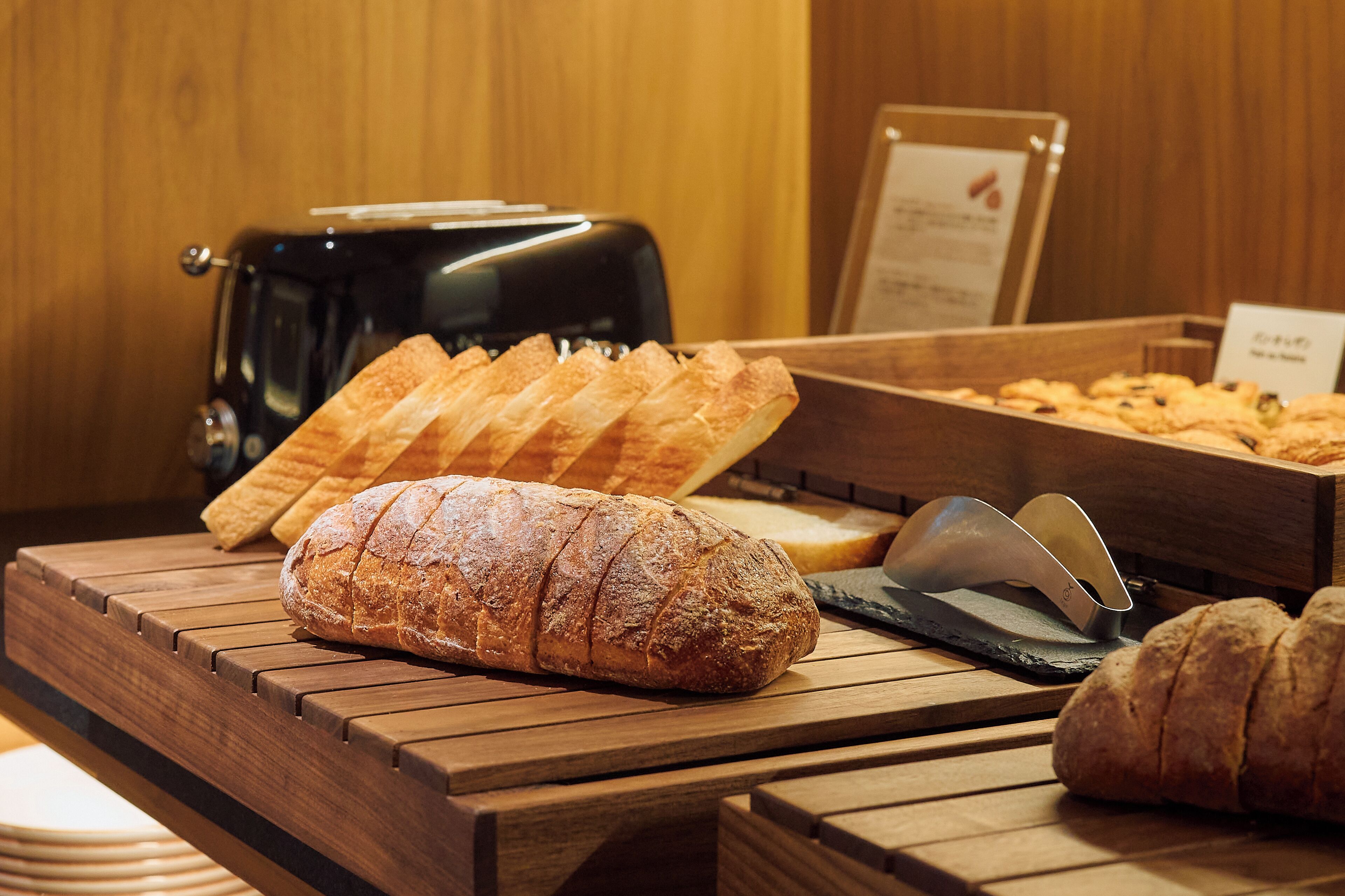 Un comptoir en bois avec une miche de pain, un grille-pain et une pancarte avec du texte.