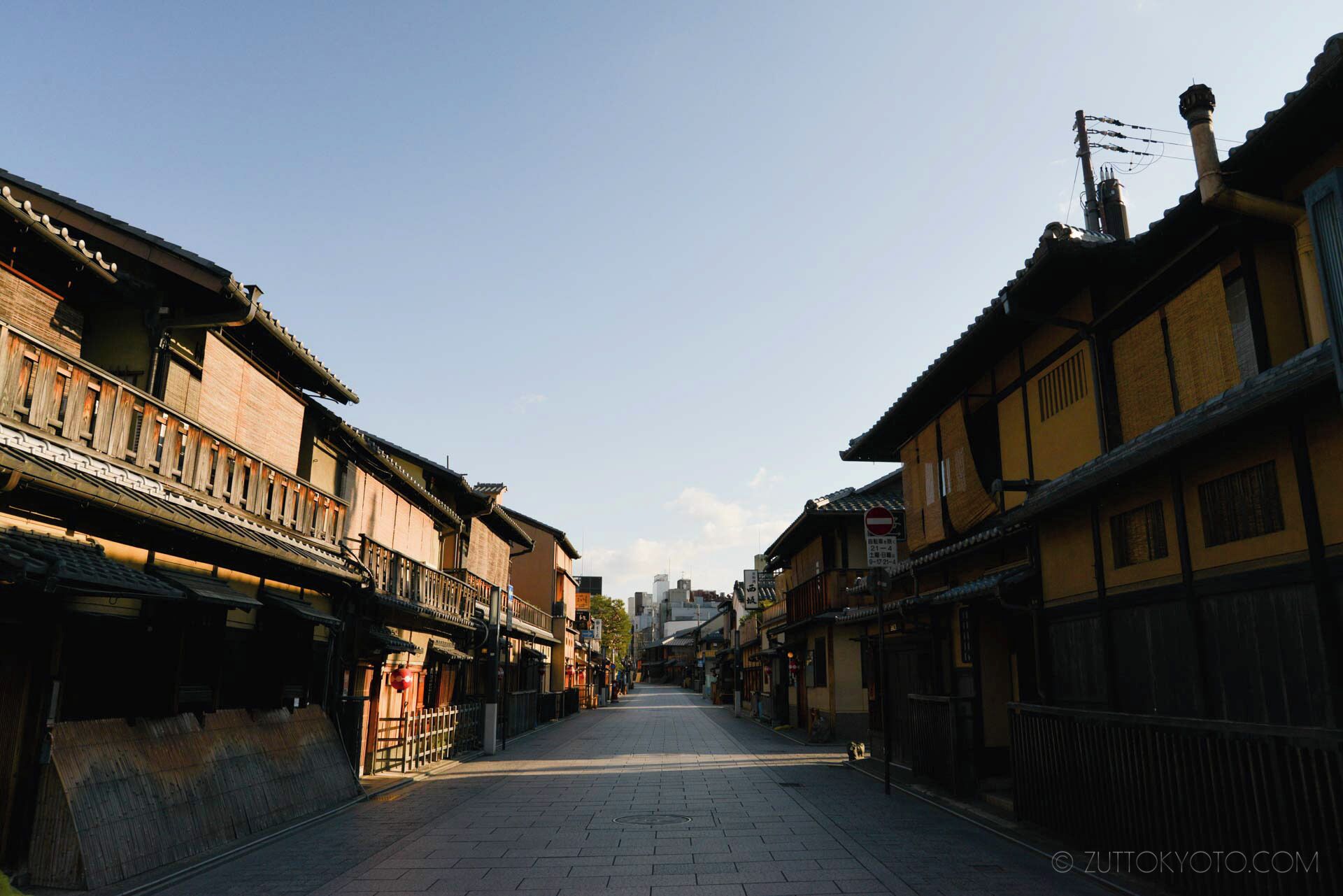 A traditional street with wooden buildings, a clear sky, and a paved walkway.