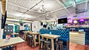 A bar area with wooden tables and blue cushioned seating. - Albion of Auckland (Auckland)