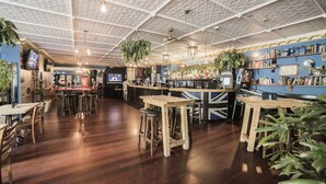 A bar area with wooden tables and stools, a counter with a menu, and hanging plants. - Albion of Auckland (Auckland)