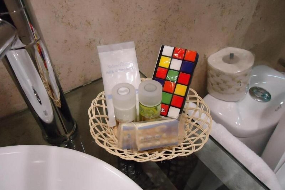 A bathroom with a white sink, a glass shower enclosure, a white toilet, and a wicker basket containing toiletries.