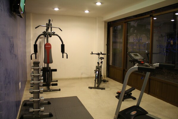 A gym with exercise equipment, a treadmill, and a window with a view of the outside. - Hotel Porto Allegro - Near Malecon (Puerto Vallarta)