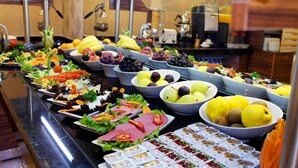 Un bufé con diversas frutas, verduras y comidas preparadas.