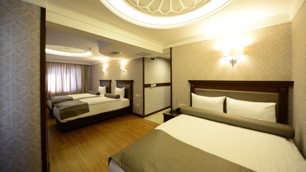 Habitación de hotel con dos camas, piso de madera y una lámpara decorativa en el techo.