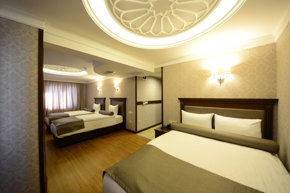 A hotel room with two beds, a wooden floor, and a decorative ceiling light fixture.