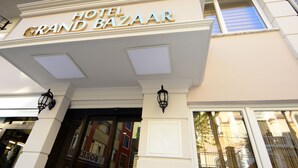 La entrada del Hotel Grand Bazaar, de estilo arquitectónico clásico, con un cartel llamativo y detalles decorativos.