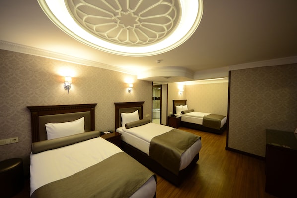 A hotel room with two beds, a wooden headboard, a mirror, and a ceiling light fixture. - Grand Bazaar Hotel (Istanbul)