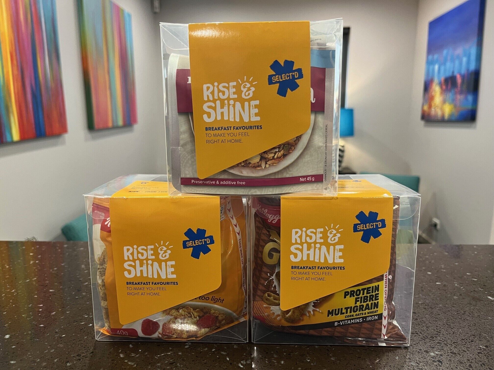 Tres cajas de cereales 'RISE & SHINE' apiladas sobre una encimera.