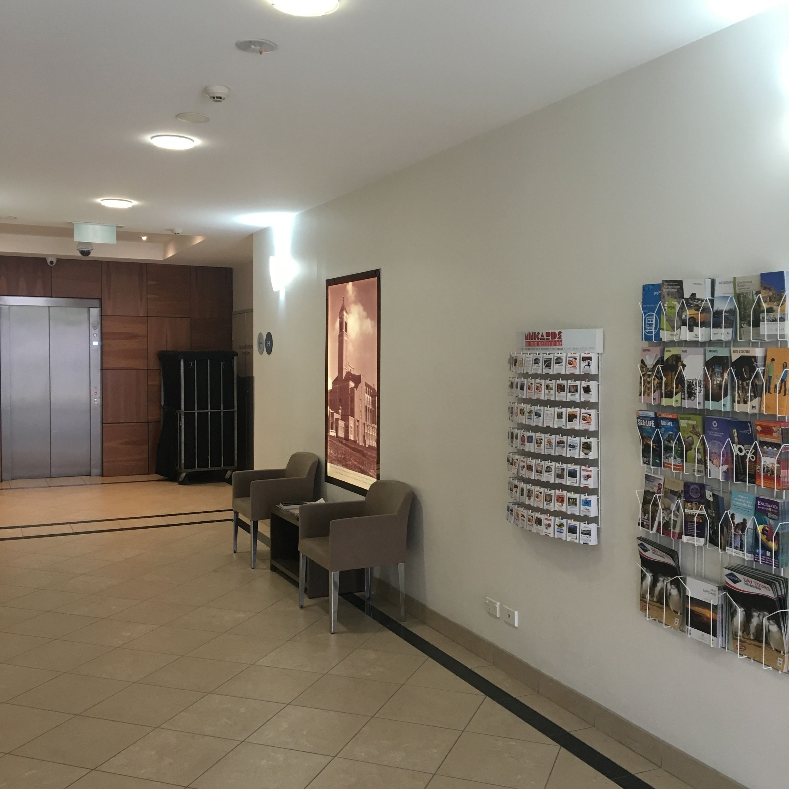 Un hall con mostrador de recepción, zona de estar y una pared con folletos turísticos.