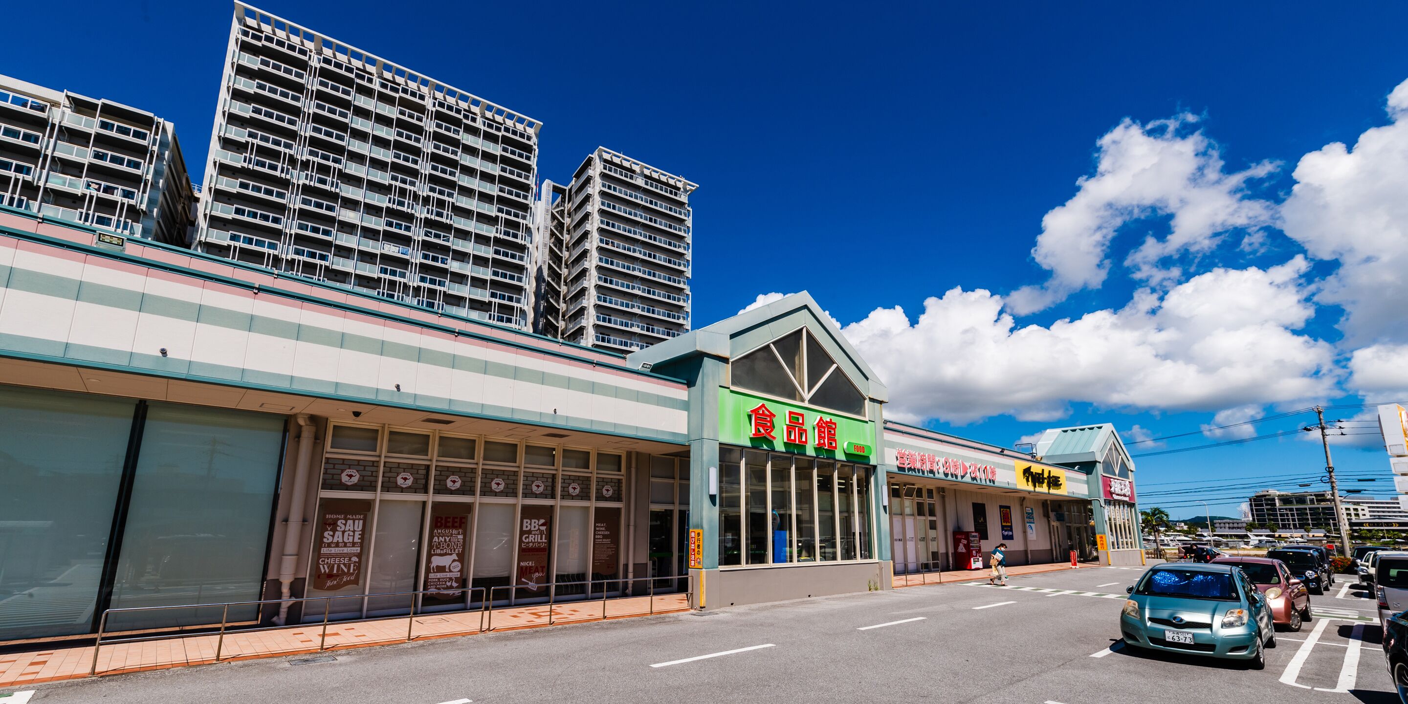 A commercial building with multiple storefronts, including a food court and a convenience store.