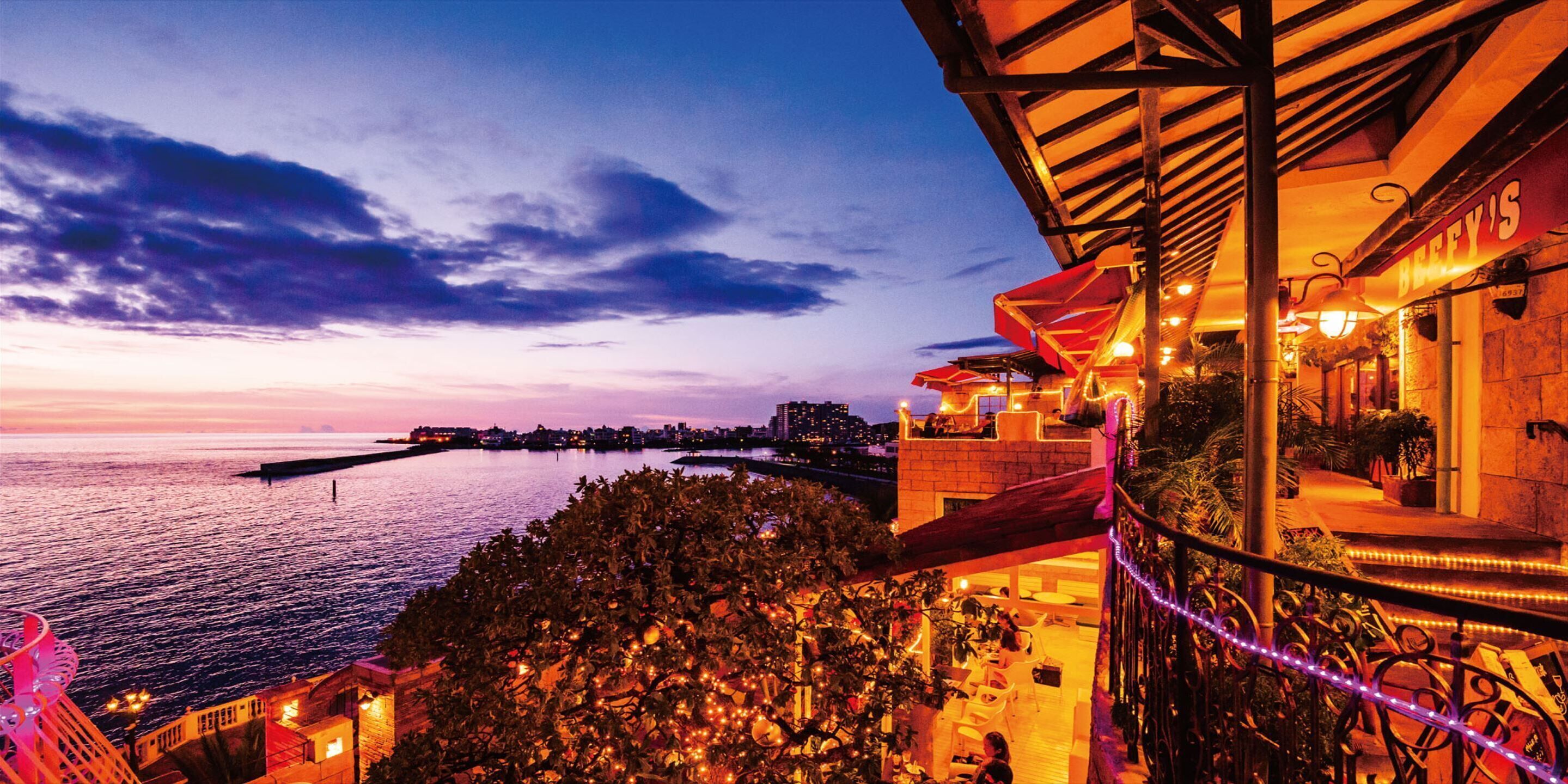 A waterfront hotel with outdoor seating and a view of the sea.