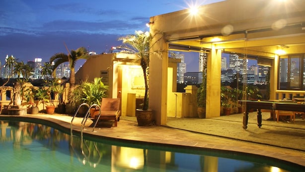 A pool area with a city view, outdoor seating, and a well-lit patio.