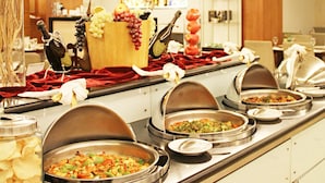 A buffet setup with multiple food stations, including a variety of dishes and a selection of fruits and vegetables.
