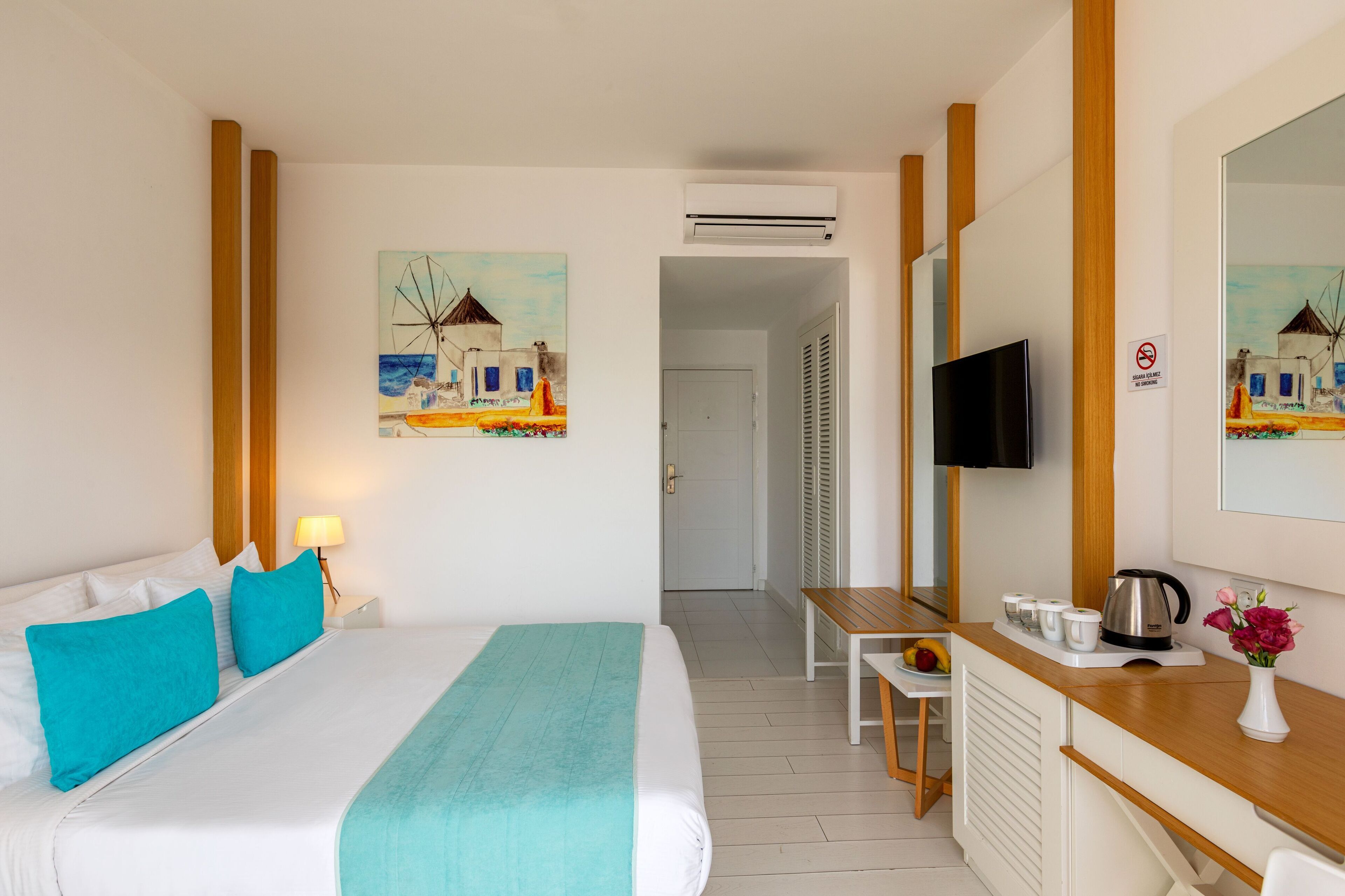 Ein Hotelzimmer mit Bett, Schreibtisch, Fernseher und einer Küchenzeile.