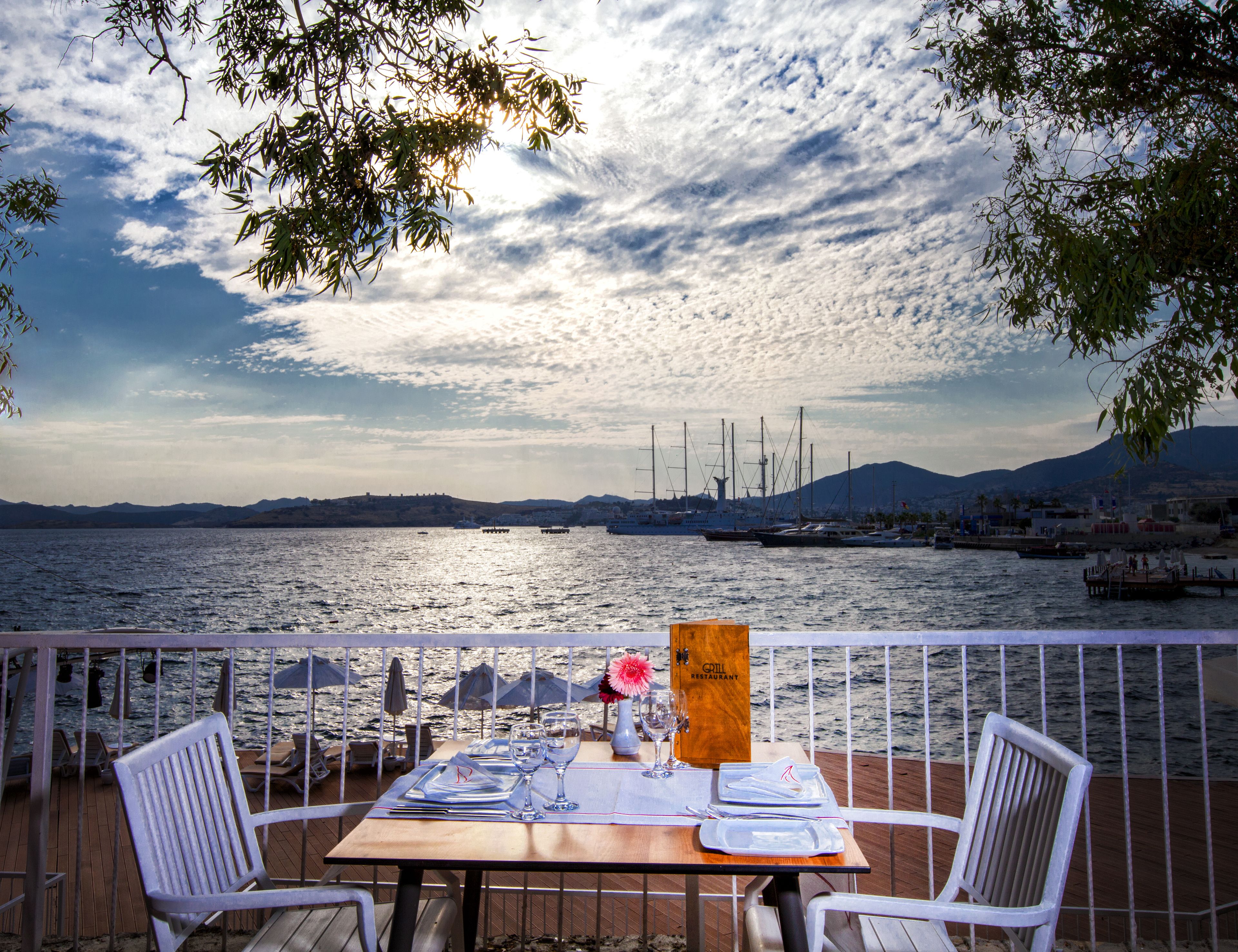 A table set for two with a view of the sea and mountains in the background.