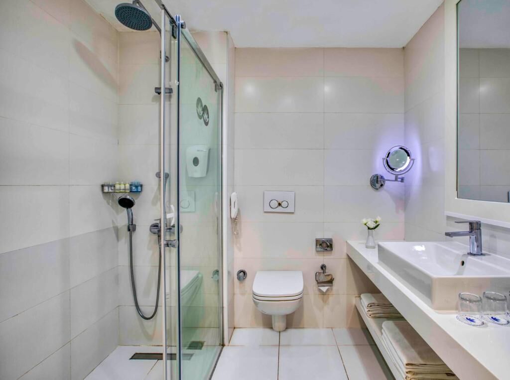 Uma casa de banho moderna com chuveiro em cabine de vidro, sanita e lavatório com espelho.
