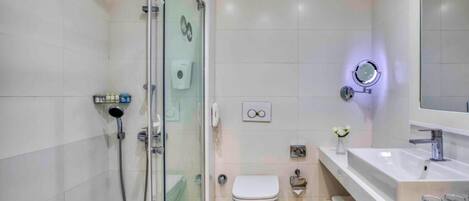 Uma casa de banho moderna com chuveiro em cabine de vidro, sanita e lavatório com espelho.
