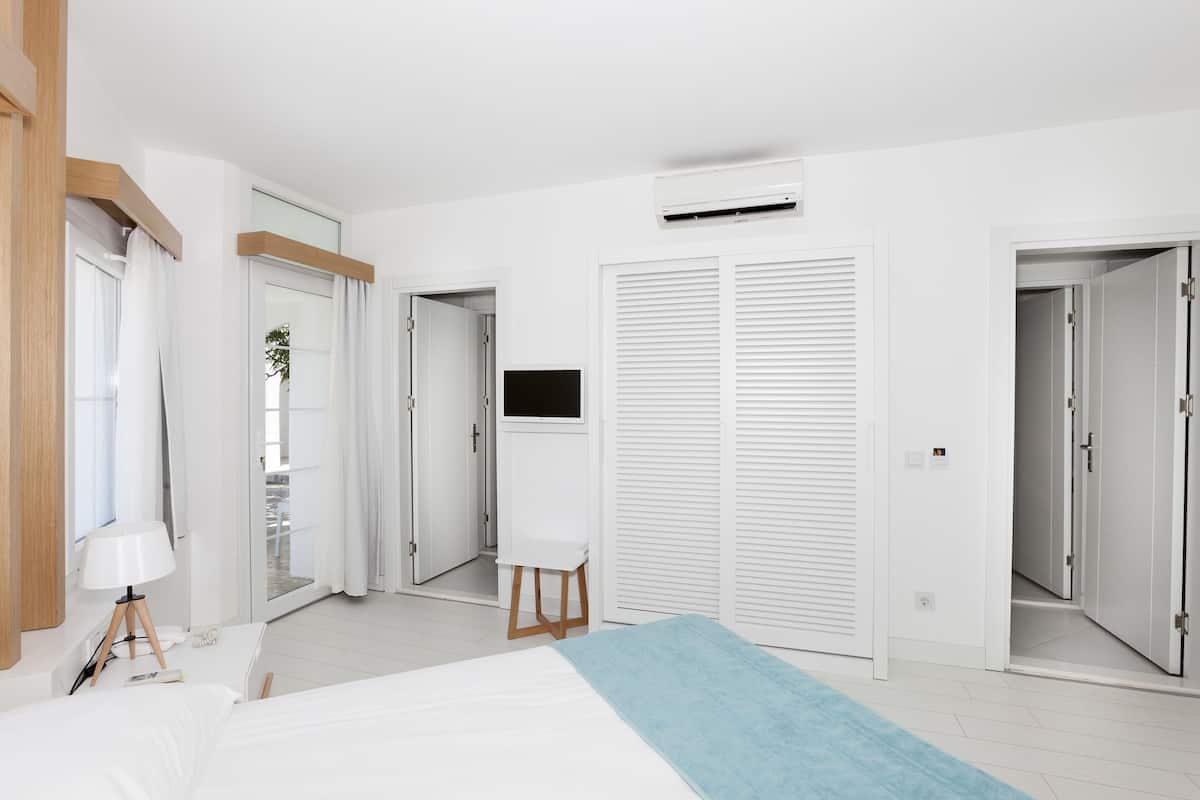 Ein modernes Hotelzimmer mit einem Bett, einem Schreibtisch, einem Fernseher und einem Schiebetürenschrank.