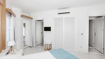 A modern hotel room with a bed, a desk, a TV, and a sliding door closet.