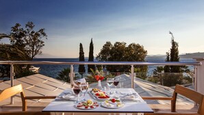 Une table dressée pour un repas, avec vue sur la mer et les montagnes.