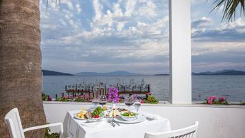 Mesa preparada para comer con vistas al mar y a las montañas.