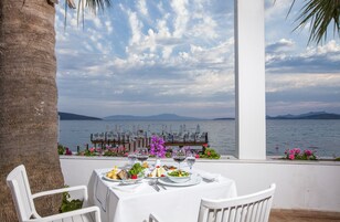 Mesa preparada para comer con vistas al mar y a las montañas.