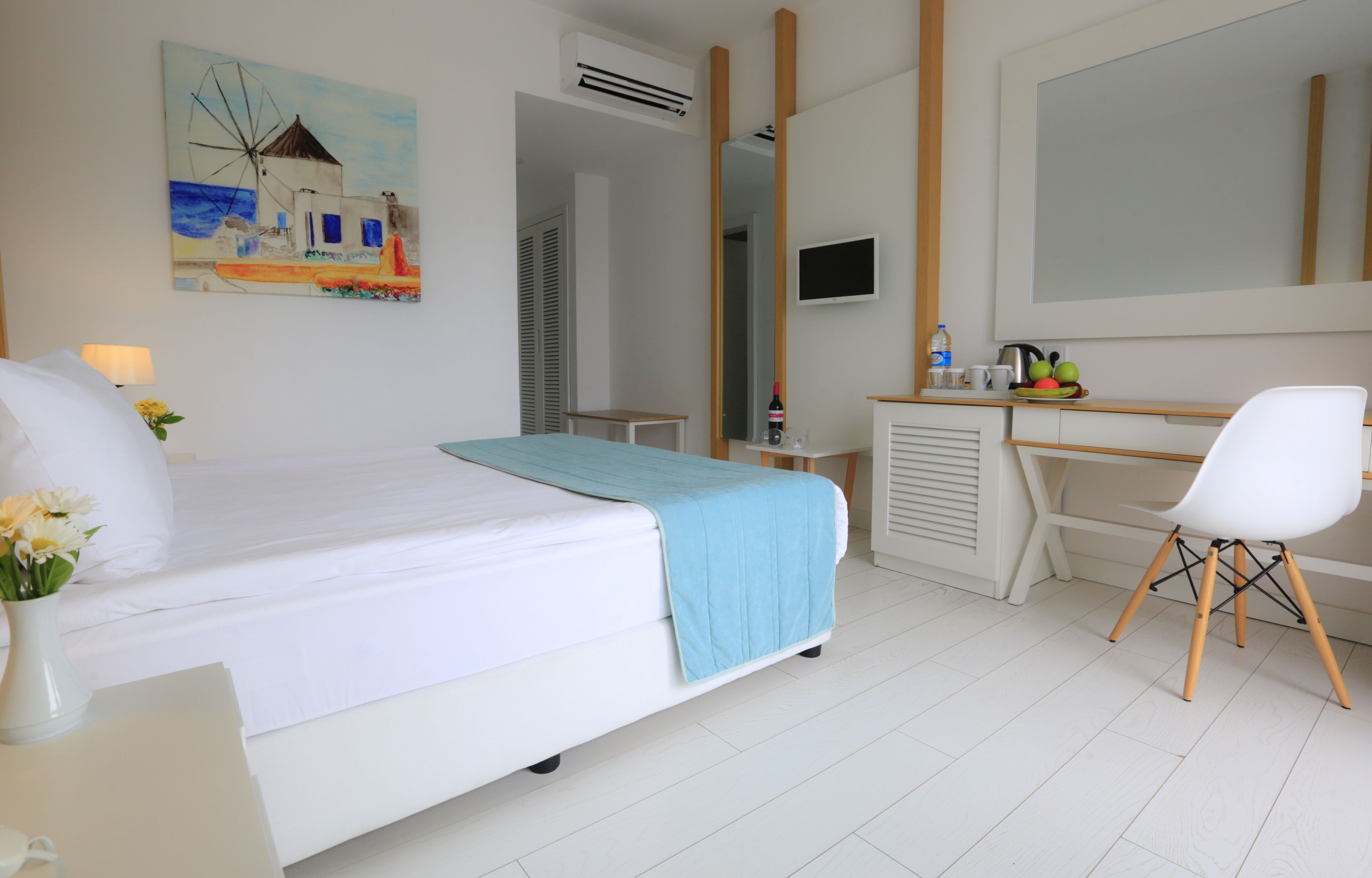 Une chambre d’hôtel avec un lit, un bureau, une chaise, une télévision et un tableau au mur.
