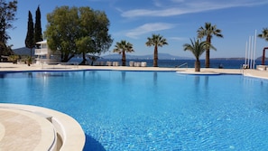 A clear blue pool with a view of the sea and mountains in the background.
