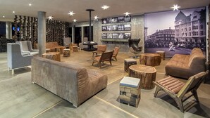 A modern lounge area with sofas, chairs, and round wooden tables. - Litli Geysir (Bláskógabyggd)