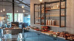 A breakfast buffet with various food items, a coffee station, and shelves with glassware and bottles. - Litli Geysir (Bláskógabyggd)