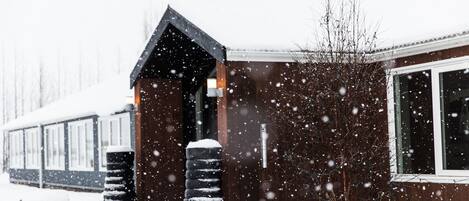 Ein hölzernes Gebäude mit geneigtem Dach und großen Fenstern, umgeben von Schnee.
