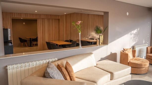 Una sala moderna con un sofá, sillones, una mesa de centro y un comedor con una mesa y sillas.