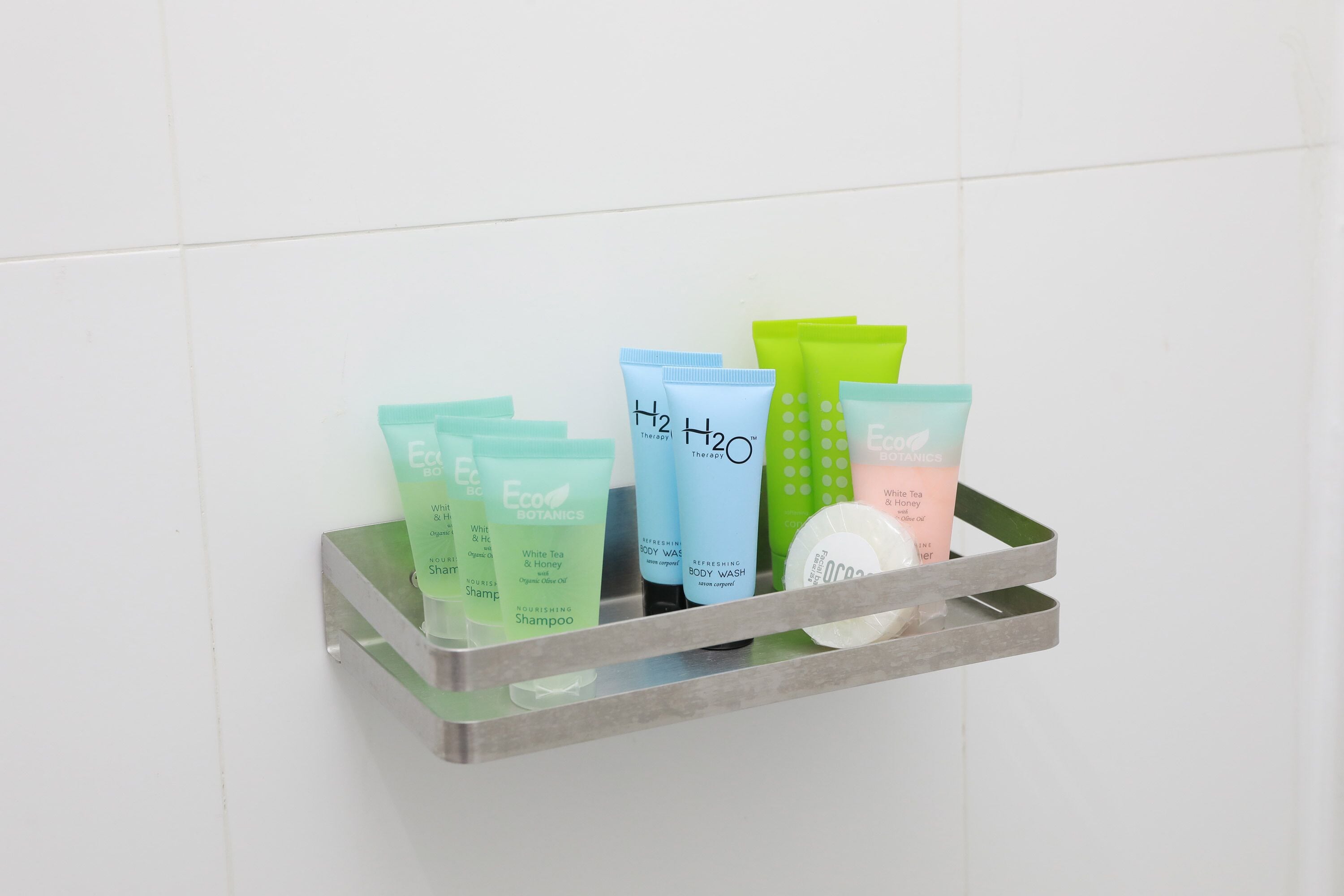 Kylpyhuoneen hyllyllä on erilaisia hygieniatuotteita, kuten vartalopesuaine, shampoo ja kasvojenpesuaine.
