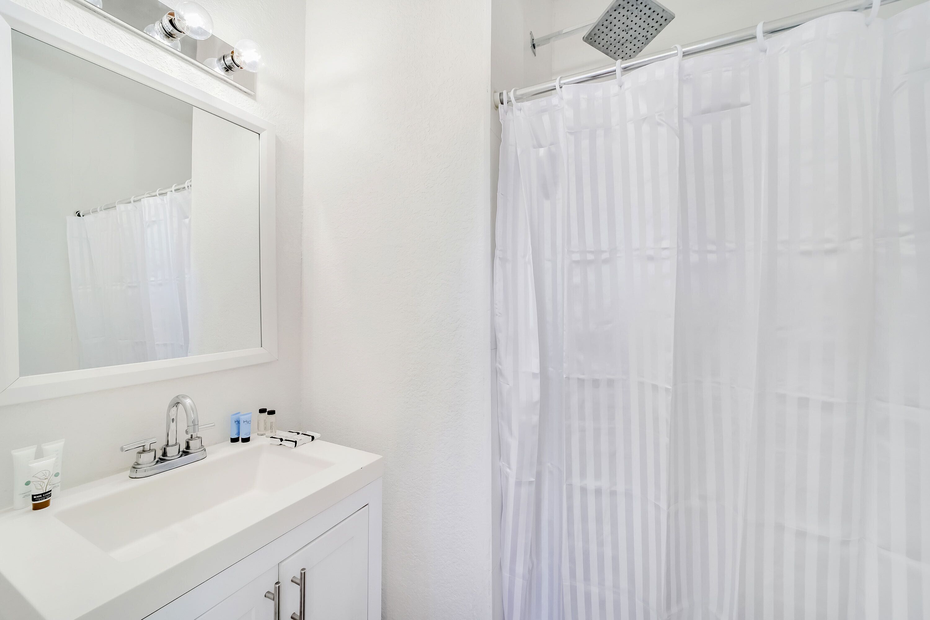 A bathroom with a white sink, mirror, and shower curtain.