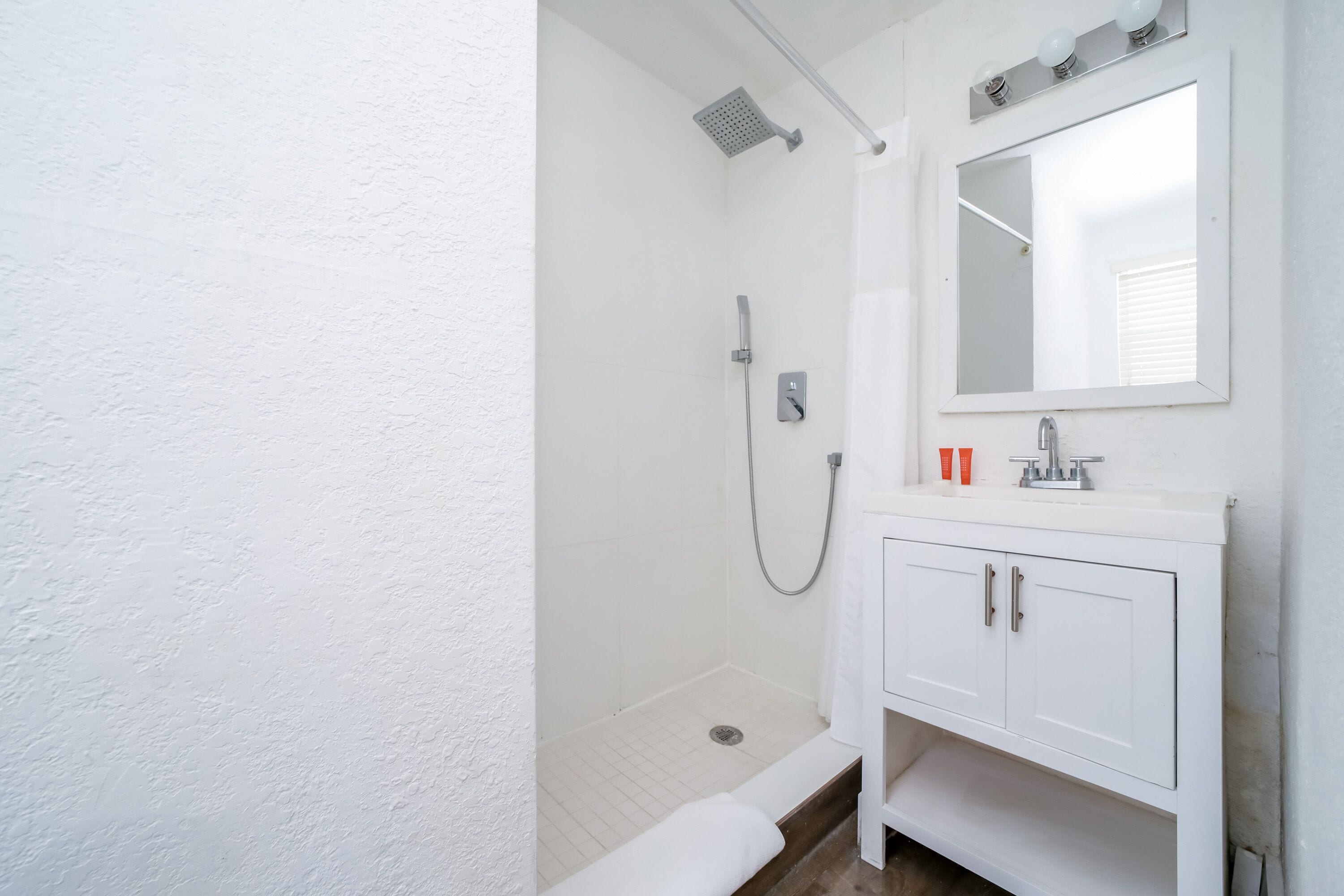 A bathroom with a shower, a sink, and a mirror.