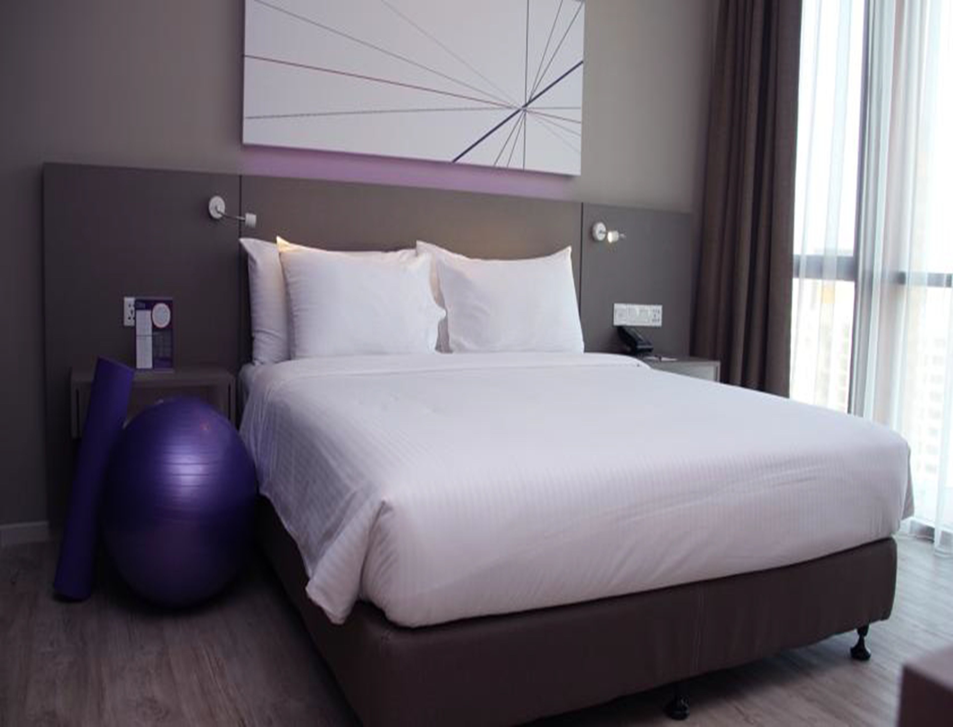 Ein modernes Hotelzimmer mit einem großen Bett, einem Fitnessball und Blick auf die Stadt.