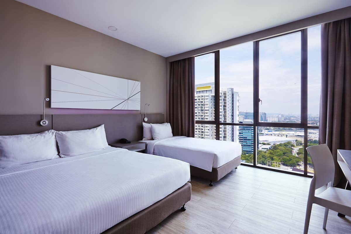 A modern hotel room with two beds, a large window with a city view, a desk, and a chair.