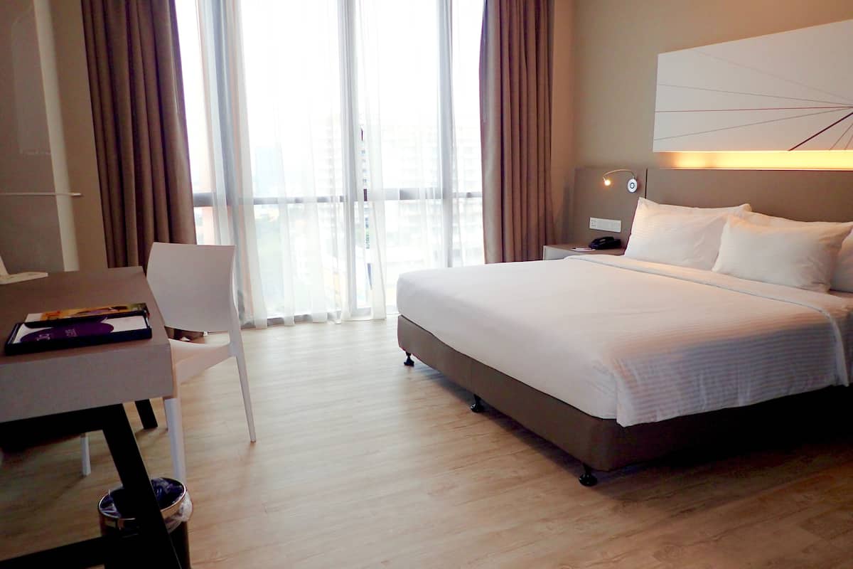 A hotel room with a bed, a desk, and a chair.