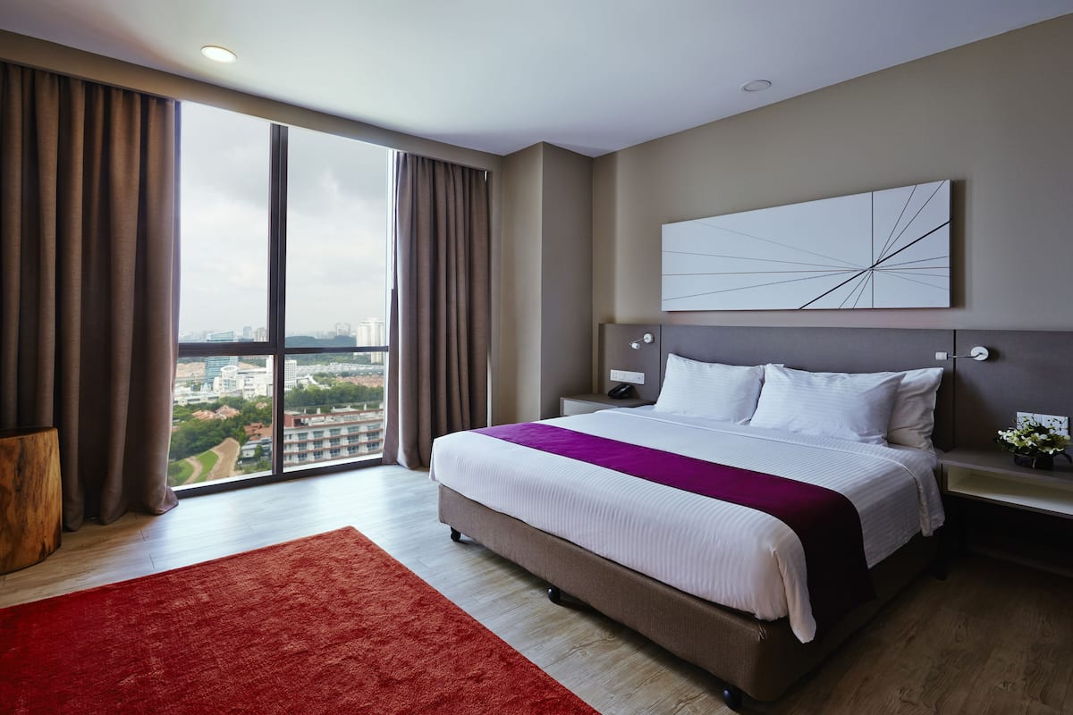 A modern hotel room with a large bed, a city view, and a minimalist decor.