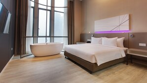 A modern hotel room with a large bed, a bathtub, and a large window with curtains. - Qliq Damansara (Petaling Jaya)