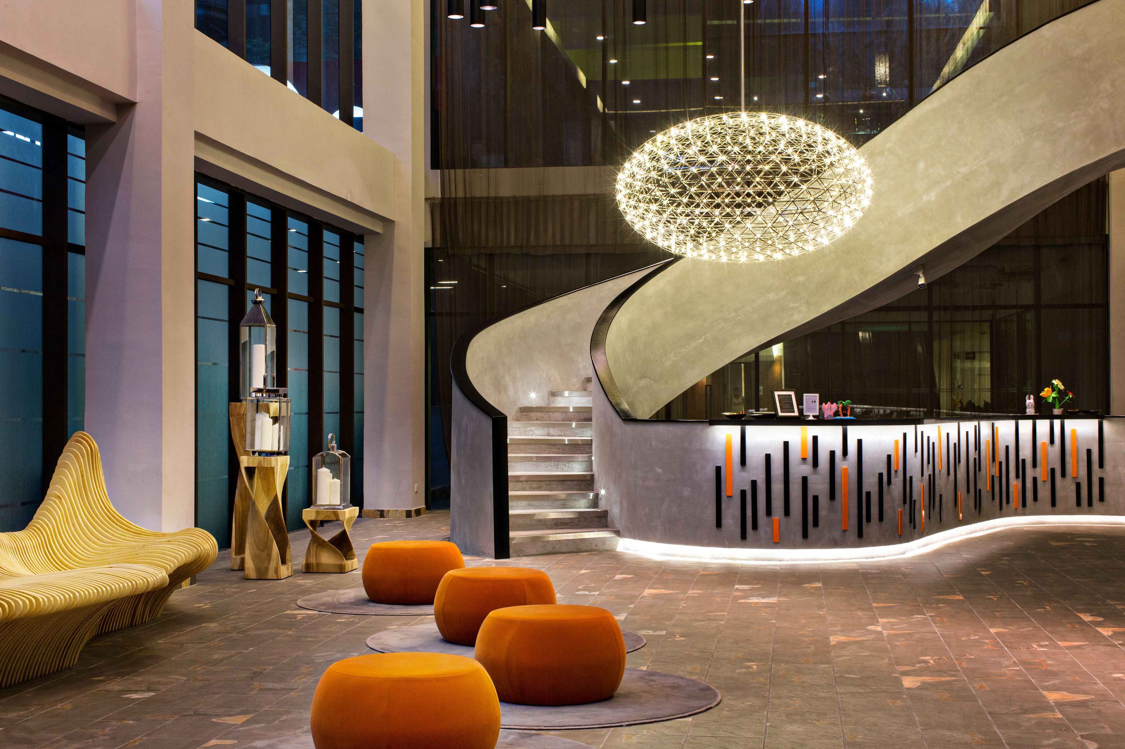 En moderne lobby med skrivebord i receptionen, en trappe og en usædvanlig rund lysarmatur.