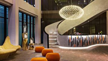 En moderne lobby med skrivebord i receptionen, en trappe og en usædvanlig rund lysarmatur.