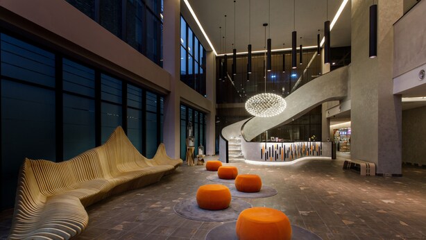 A spacious lobby with a modern design, featuring a curved bench, orange ottomans, and a unique spherical light fixture. - Qliq Damansara (Petaling Jaya)