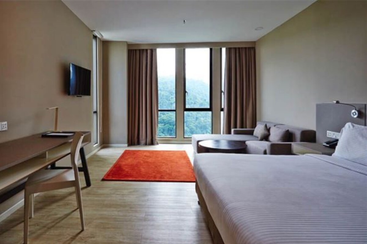 A modern hotel room with a large bed, a desk, a TV, and a view of the outdoors.