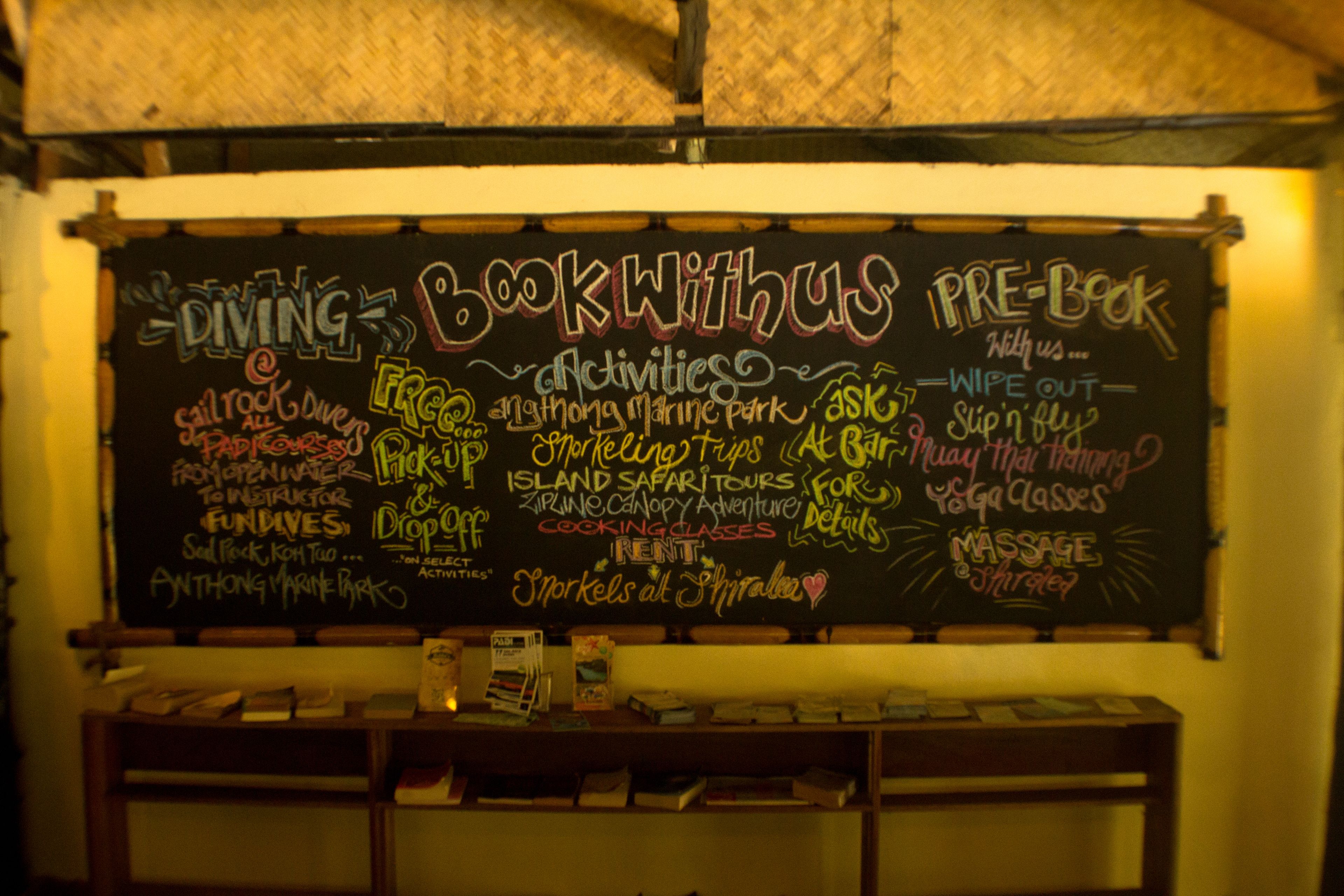 A chalkboard with various activities and services listed, such as diving, book with us, pre-book, and spa classes.