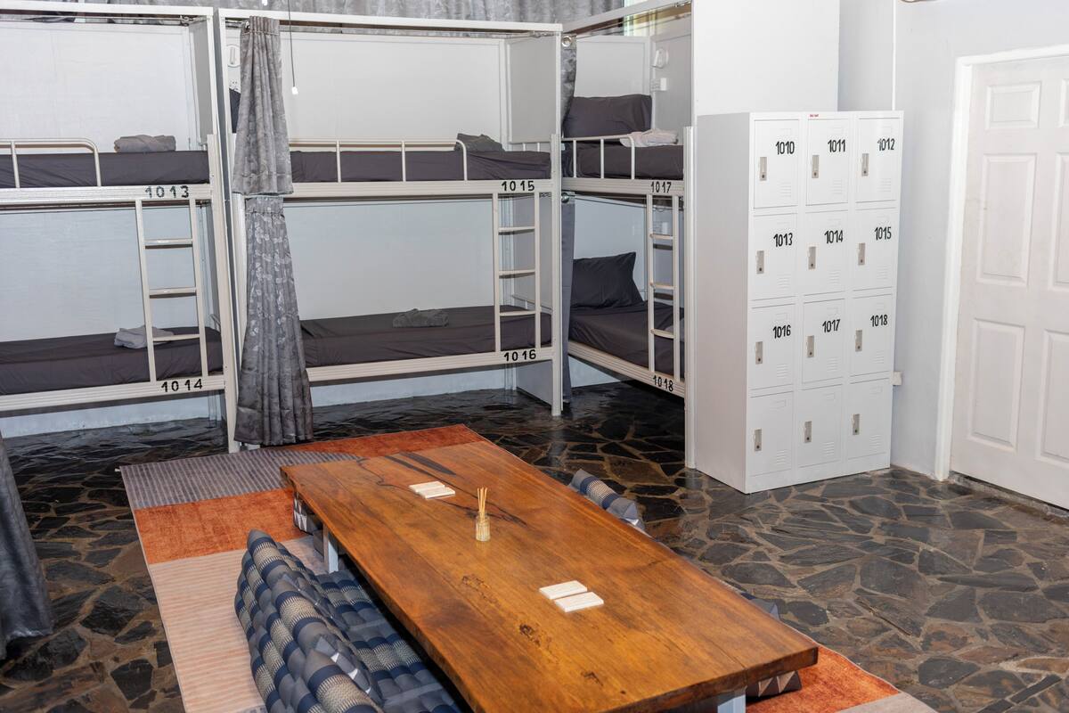 Quarto de dormitório com beliches, uma mesa de madeira e armários.