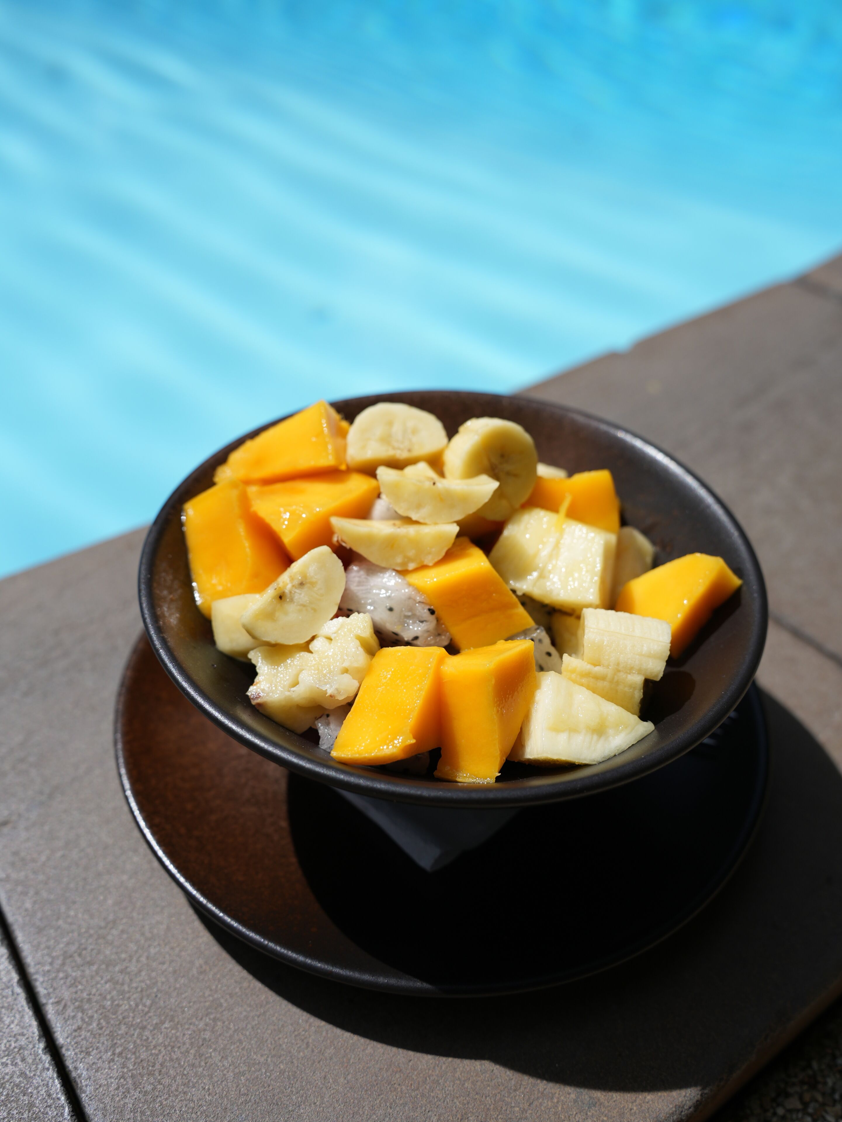 A bowl of fruit next to a pool.